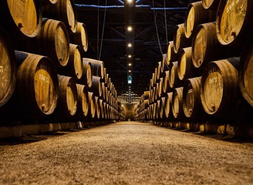 Old aged traditional wooden barrels with wine in a vault lined up in cool and dark cellar in Italy, Porto, Portugal, France