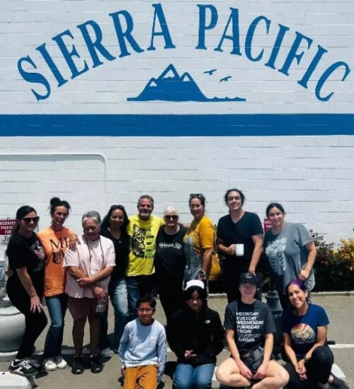Group of people smiling together in front of a “Sierra Pacific” wall, symbolizing unity and community. teamwork and unity